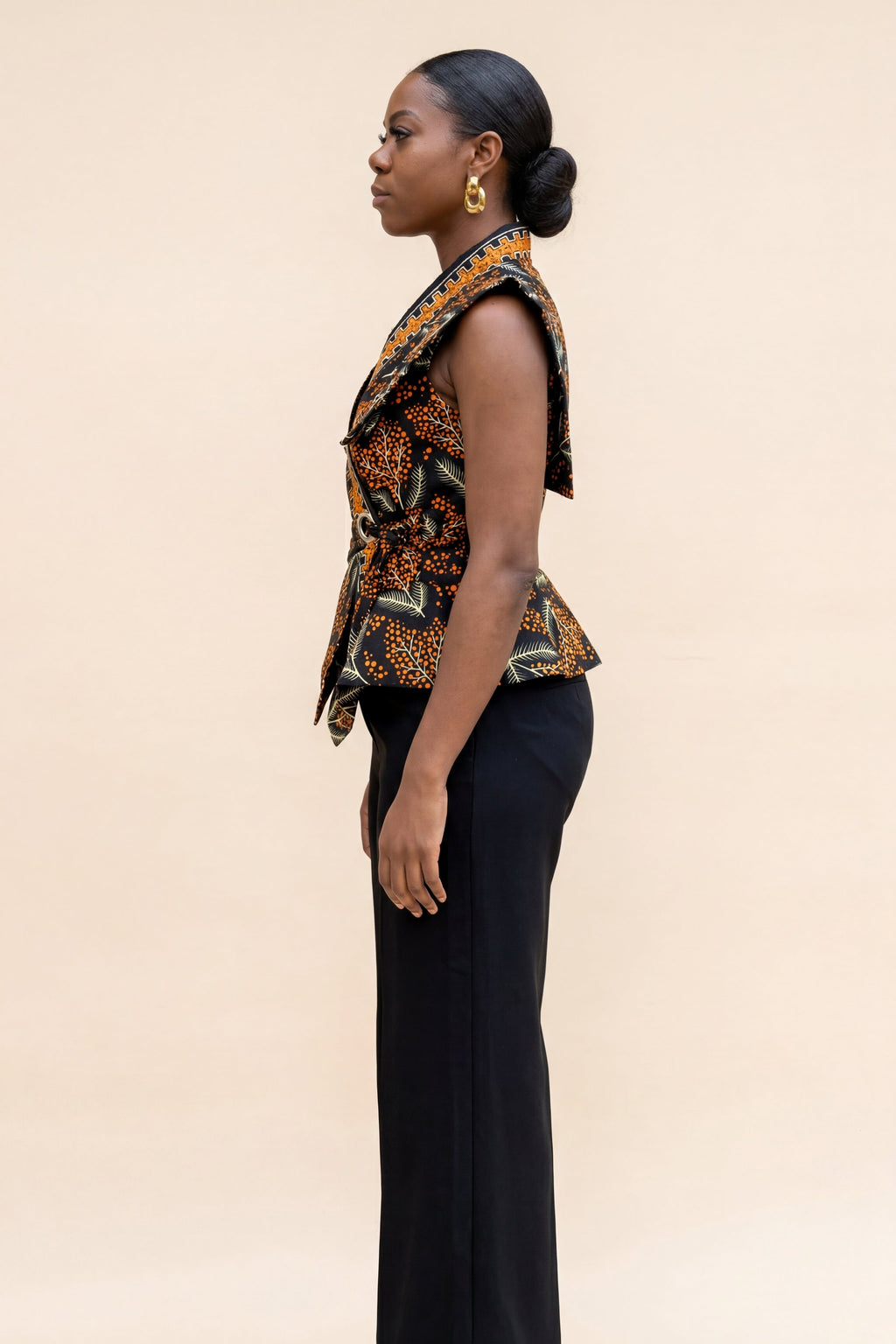Woman wearing a patterned top and black pants on a beige background