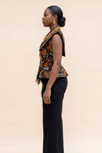 Woman wearing a patterned top and black pants on a beige background