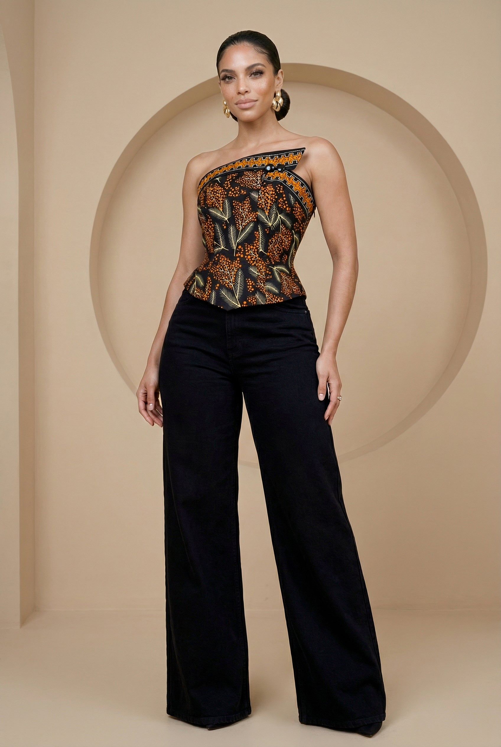 Woman wearing a strapless top with a pattern and black pants against a beige background