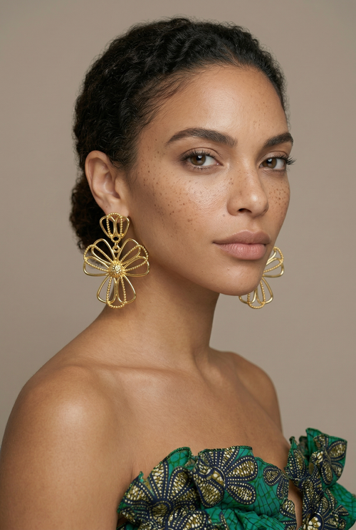 Woman wearing gold floral earrings against a neutral background